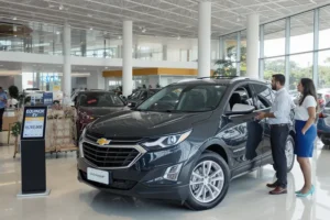 Vendedor Chevrolet apresenta o Equinox EV para casal interessado em concessionária com o novo preço exibido.