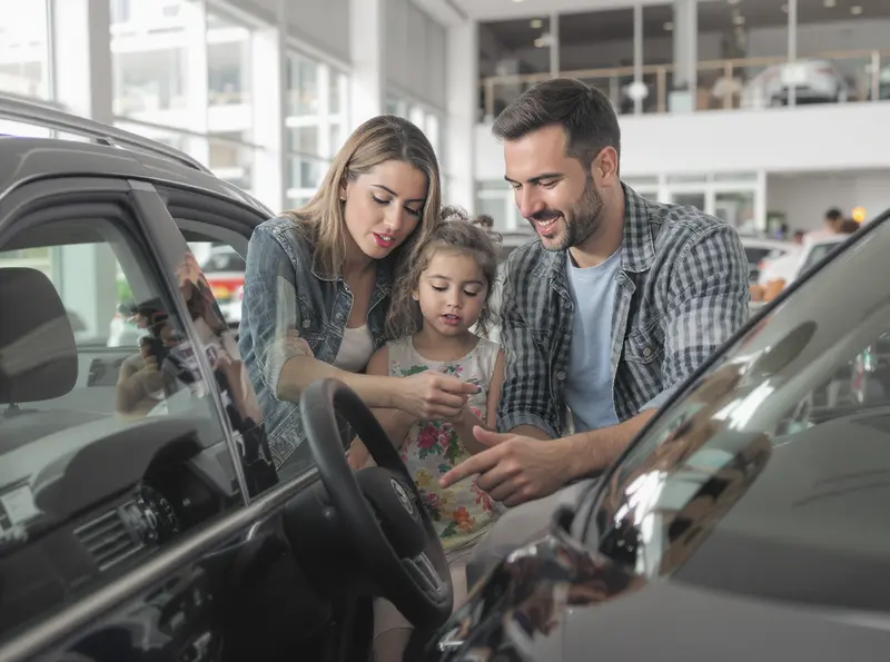 Volkswagen busca retomar qualidade e preços competitivos para recuperar mercado Família brasileira observa e discute um carro Volkswagen novo em concessionária.