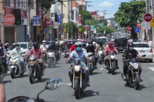 Rua movimentada em Caruaru, PE, repleta de motocicletas no trânsito, destacando a predominância sobre os carros.