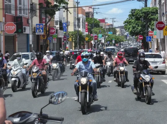 Rua movimentada em Caruaru, PE, repleta de motocicletas no trânsito, destacando a predominância sobre os carros.
