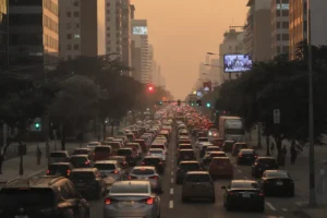 Engarrafamento em cidade brasileira com ar poluído ao entardecer, destacando a complexidade do trânsito.