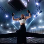 Lutadora de MMA comemora vitória sobre a grade do octogono