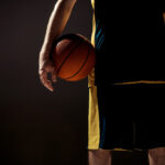 jogador de basquete segurando uma bola embaixo do braço