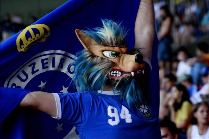 Torcedor do Cruzeiro segurando uma bandeira e usando uma máscara de raposa