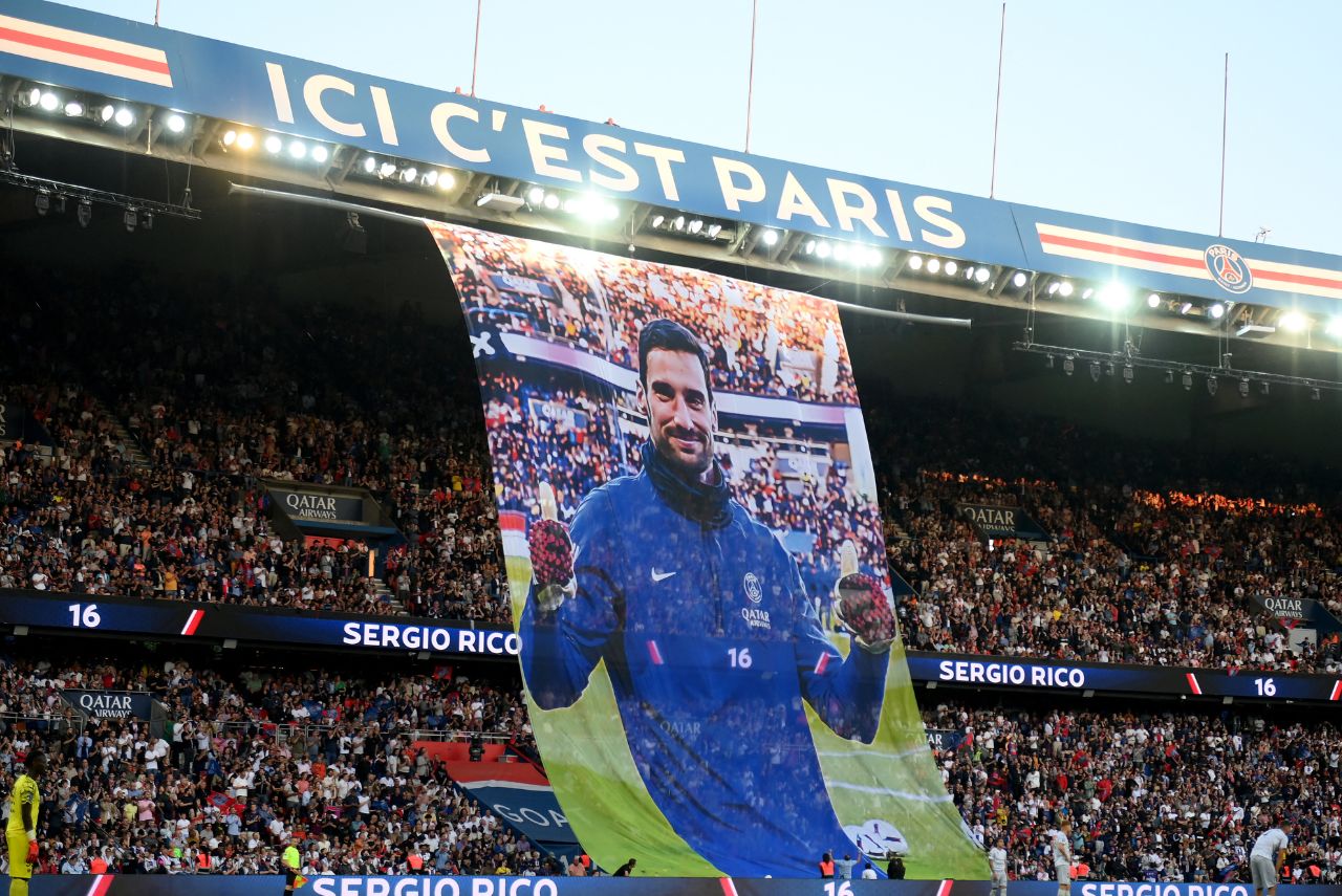 Arquibancada de estádio do PSG com foto do jogador Sergio Rico esticada sobre o público.