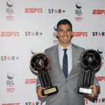 Jogador Luis Suarez sorrindo e segurando dois trofeus da Bola de Prata