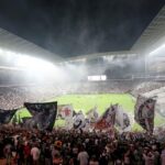 Estádio do Corinthians visto do meio de sua torcida na arquibancada, em festa durante o jogo.