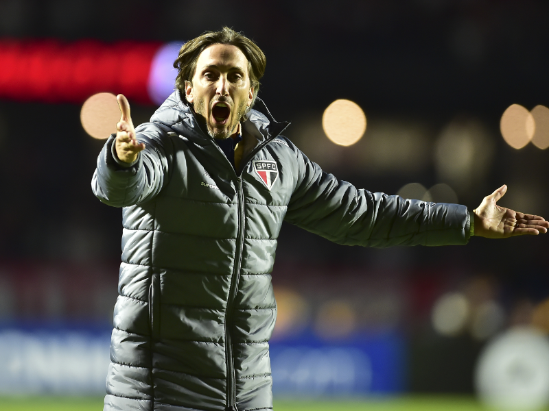 Close-up do técnico Luis Zubeldía com expressão de frustração durante coletiva de imprensa.