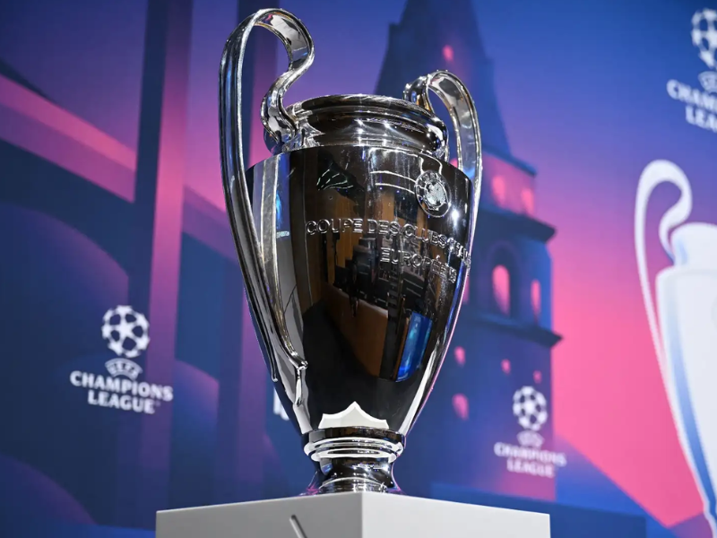 Estádio de futebol vibrante com torcedores e a logo da Champions League 2025 no céu.