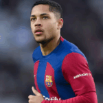 Estádio de futebol lotado com torcedores e bola em movimento.