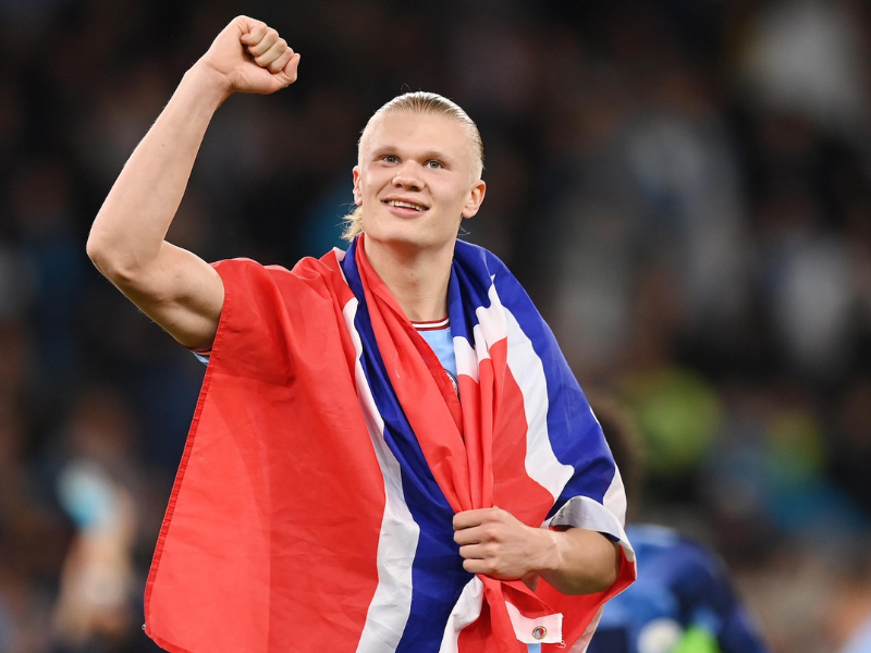 Erling Haaland driblando em um jogo noturno da Champions League.