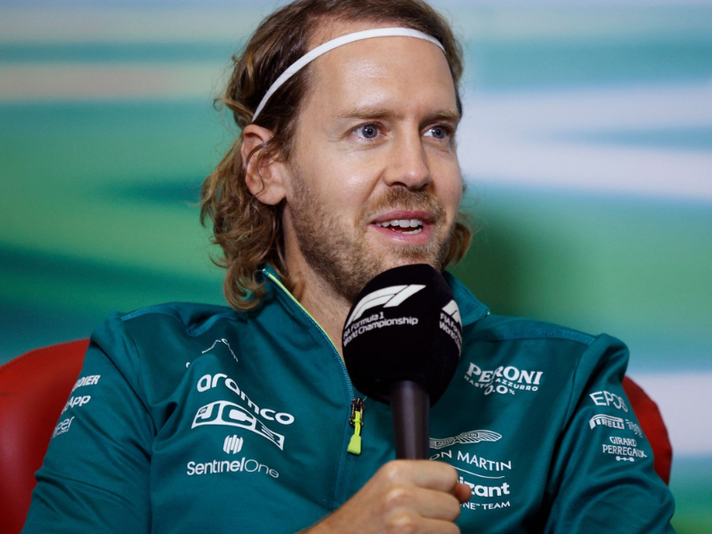 Sebastian Vettel sorrindo com macacão vermelho da Ferrari.