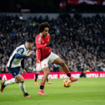 Jogador do Tottenham dribla defensor do Manchester United durante partida acirrada.