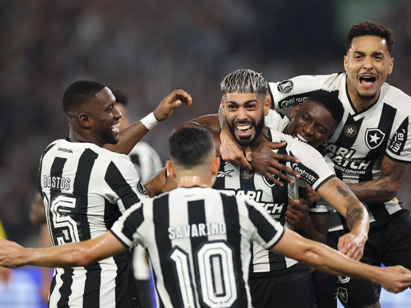 Estádio lotado com torcida vibrante, jogador do Botafogo em ação, representando a reconstrução do clube.