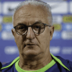 Imagem de close-up de Dorival Júnior refletindo em seu escritório.