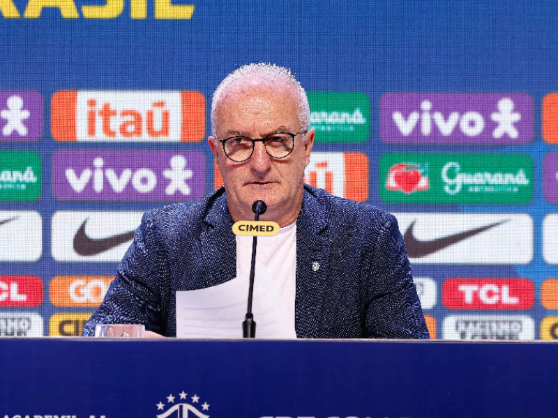 Endrick, Ederson e Paquetá em um campo de futebol com a torcida brasileira ao fundo.