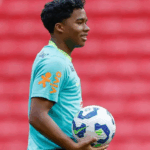 Close-up de Endrick sorrindo com a camisa da Seleção Brasileira.