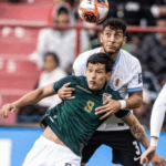 Jogadores de Bolívia e Uruguai disputando a bola no alto durante partida em La Paz.