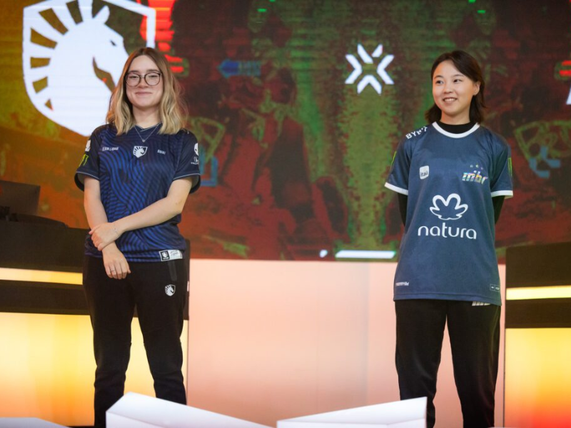 Jogadoras concentradas em competição de Valorant com luzes neon.