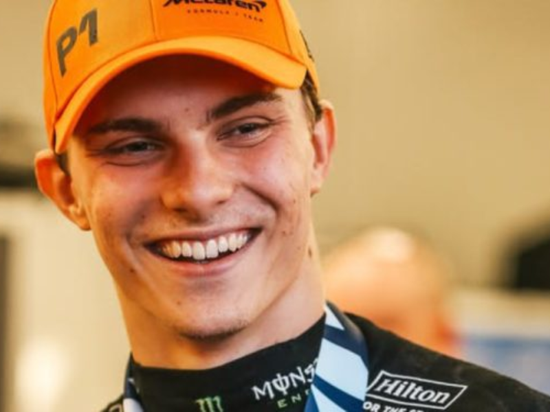 Oscar Piastri sorrindo no pit lane da McLaren.