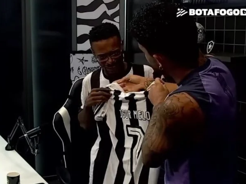 Foto de Igor Melo emocionado com camisa do Botafogo no podcast.