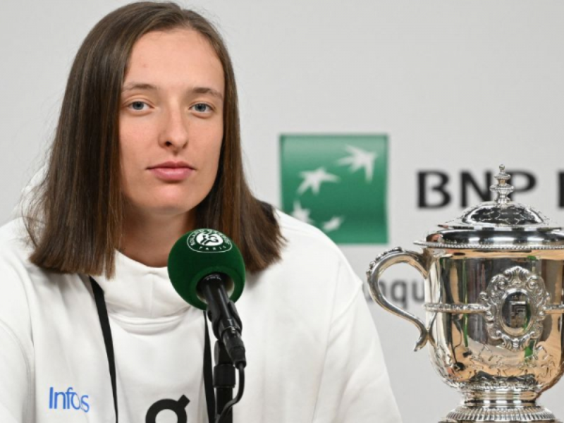 Iga Swiatek sendo escoltada por seguranças após um treino de tênis.