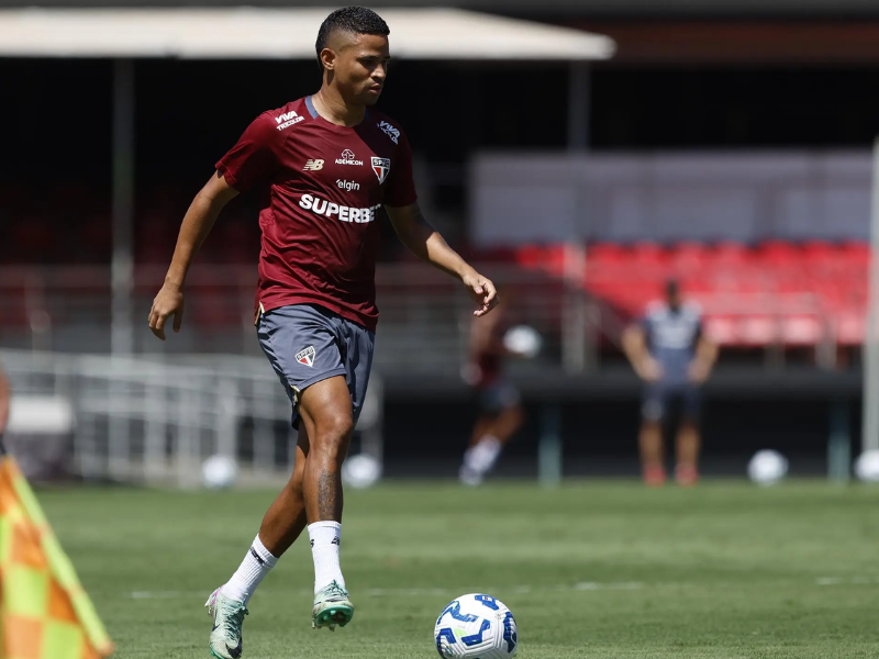 Jogador do São Paulo FC correndo em direção ao gol em um estádio vibrante.