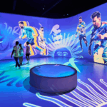 Imagem da exposição The Messi Experience em São Paulo, com fãs interagindo com hologramas de Messi.