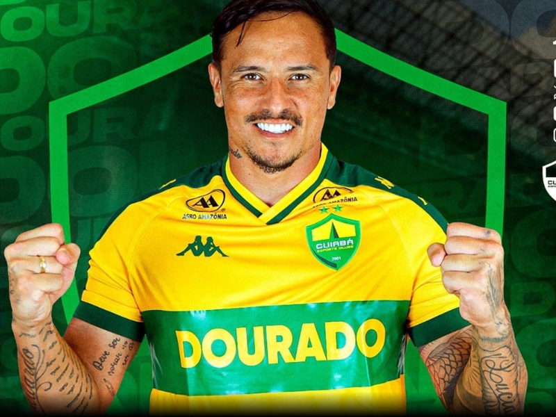 Edu sorrindo ao segurar a camisa do Cuiabá durante sua apresentação.