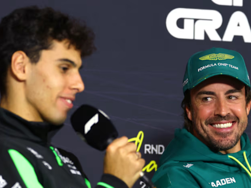 Fernando Alonso e Gabriel Bortoleto sorrindo no paddock de F1.