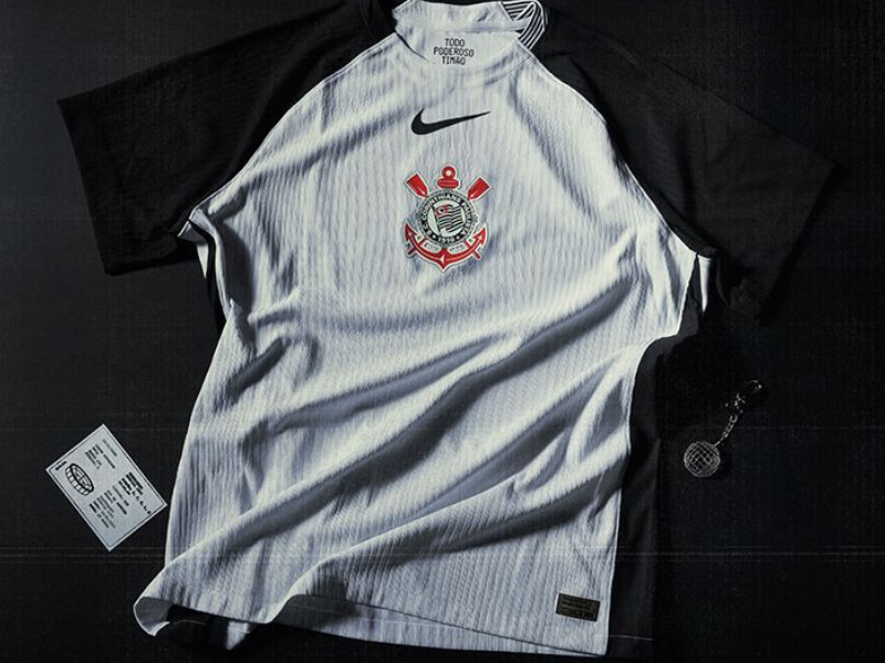 Torcedor do Corinthians vestindo a nova camisa preta e branca em frente ao estádio.