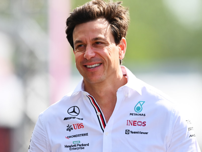 Foto ultrarrealista de Toto Wolff, diretor da Mercedes F1, no box da equipe, olhando para a pista com semblante sério e concentrado.