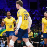 Darlan, jogador de vôlei brasileiro, saltando para atacar a bola com força em uma quadra de vôlei durante uma partida.