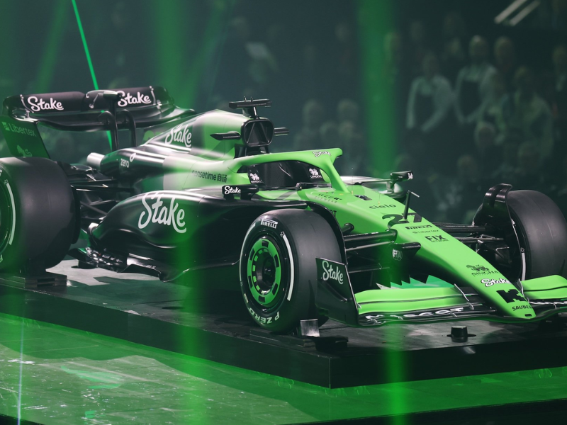 Carro de Fórmula 1 da equipe Sauber com detalhes em verde e cinza em alta velocidade no circuito de Silverstone.
