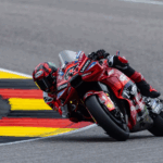 Francesco Bagnaia, piloto de MotoGP, celebra com o punho erguido ao lado de sua motocicleta Ducati, na pista de Brno.