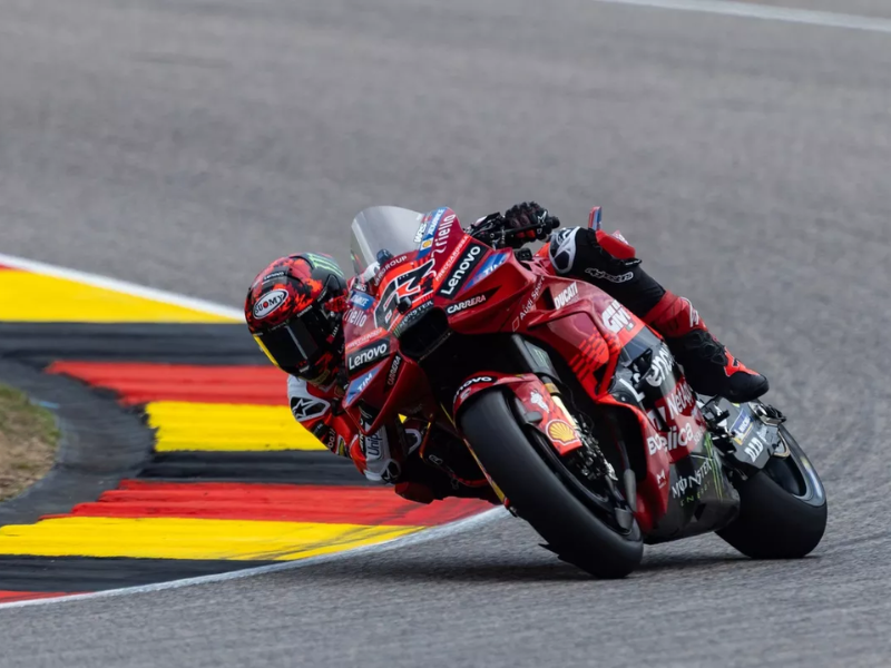 Francesco Bagnaia, piloto de MotoGP, celebra com o punho erguido ao lado de sua motocicleta Ducati, na pista de Brno.
