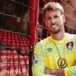 Goleiro Neto, 36 anos, em pé no campo do Estádio Nilton Santos, vestindo o uniforme preto e branco do Botafogo.