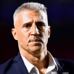 Visão noturna ultrarrealista do MorumBIOS, com holofotes iluminando o campo. Um jogador do São Paulo celebra um gol, com arquibancadas cheias de torcedores ao fundo.