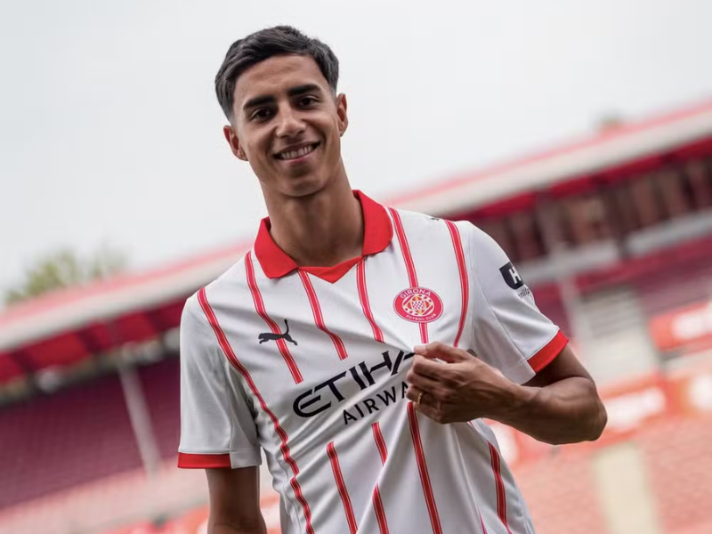 Retrato de Vitor Reis, jogador de futebol brasileiro, vestindo o uniforme do Girona FC, em um campo de treino.