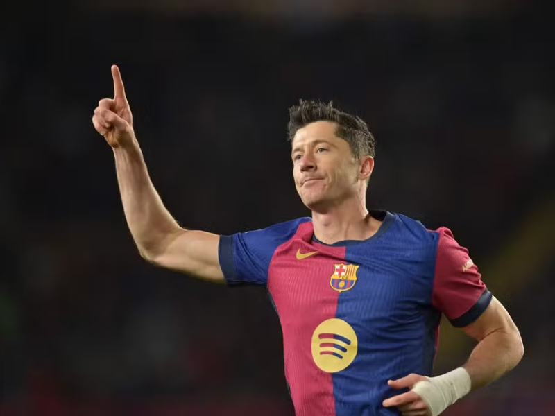 Robert Lewandowski em close, com expressão de dor na coxa esquerda, sentado em banco de vestiário.