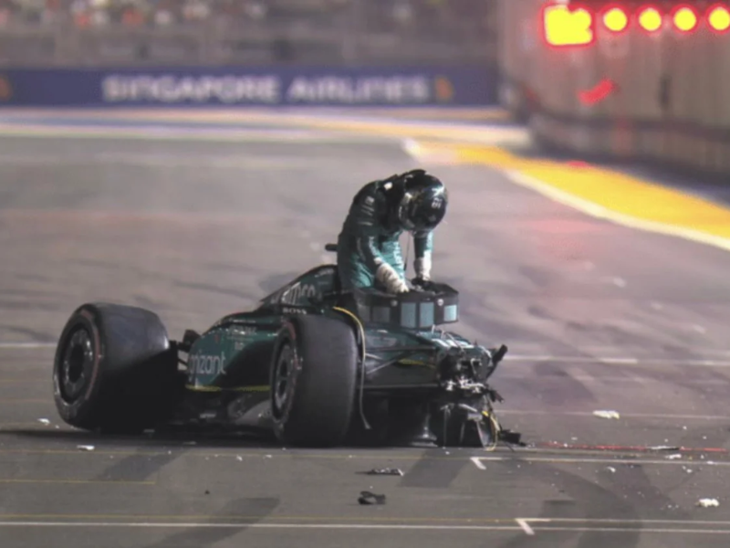 Carro de Fórmula 1 Aston Martin AMR23 gravemente danificado após uma colisão frontal com as barreiras, com detritos espalhados na pista de Zandvoort.