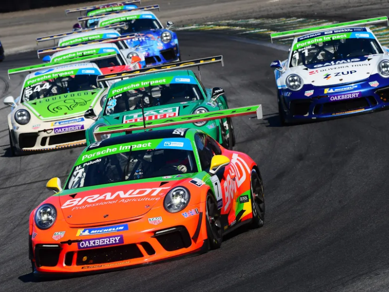 Vista aérea de um Porsche 911 GT3 Cup branco correndo em alta velocidade na pista do Circuito do Estoril.