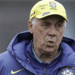 Um estádio de futebol futurista iluminado à noite, com projeções holográficas em campo e torcedores nas arquibancadas, simbolizando a Copa do Mundo de 2026.