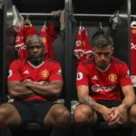 Dois jogadores do Manchester United sentados em um vestiário, com expressões de preocupação.