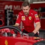 Engenheiro da Ferrari em um box de Miami, examinando uma peça leve do carro F1.